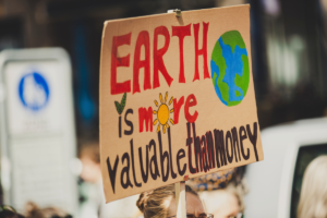 protestor holding sign reading "earth is more valuable than money"