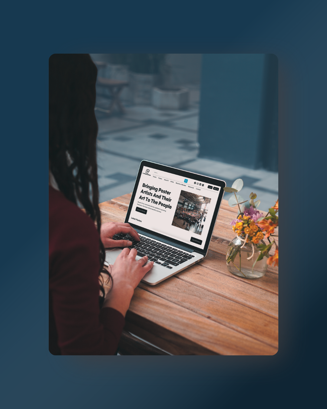 a woman is sitting in a modern office looking on her laptop at The Poster Institute's website