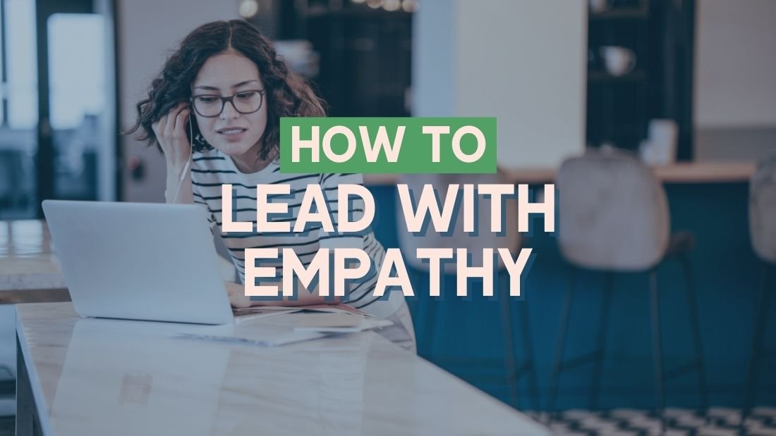 woman working at modern office setting, sitting on her laptop with her earbud in place. The writing in front of her reads 'how to lead with empathy'