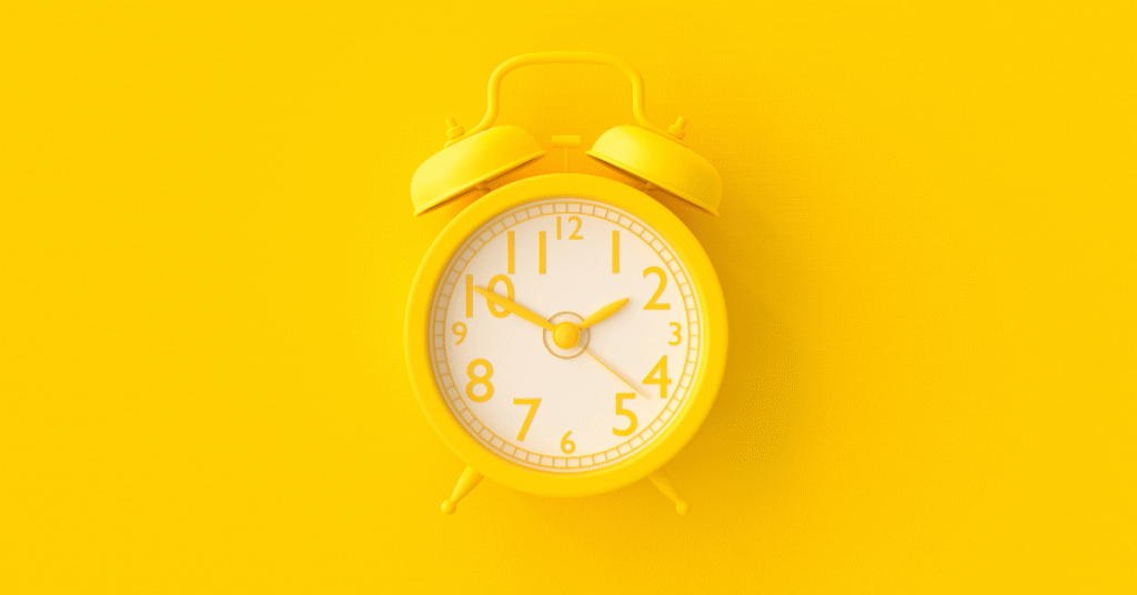 Yellow analog clock on a bright yellow background representing time management and focus.