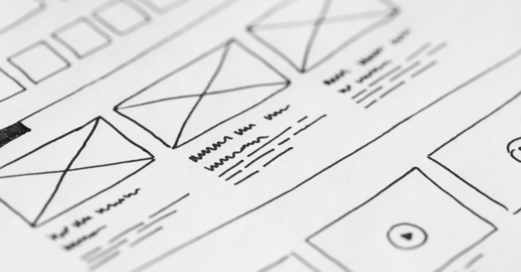 Close-up of hand-drawn website wireframes on white paper, representing web design planning and layout strategy.
