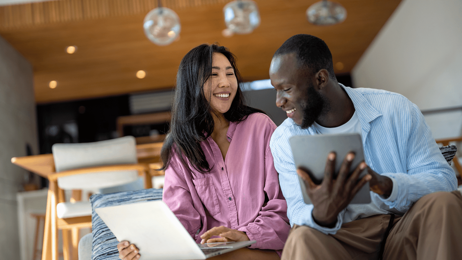 Smiling couple using a laptop at home. Warm connection, remote work, and modern digital lifestyle.