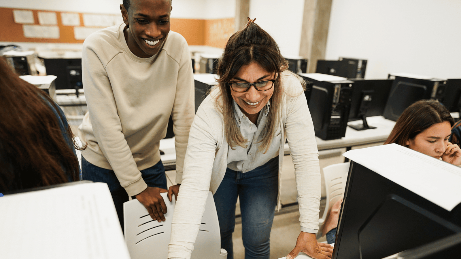 Coworkers discussing a project on a laptop in a bright open office. Creative teamwork and productivity.