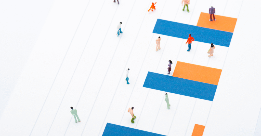 High-angle view of miniature people walking across a simplified data chart with highlighted bars