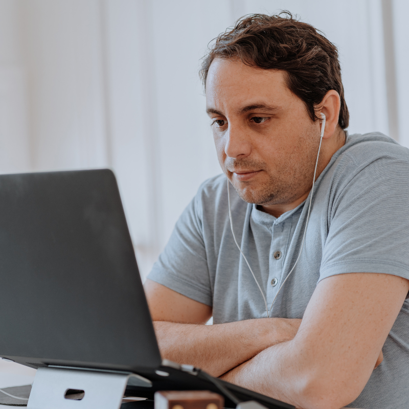 man looking at his laptop wearing headphones