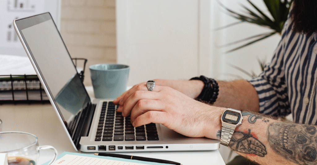 Tattooed Person Using Laptop in a bright clean office setting