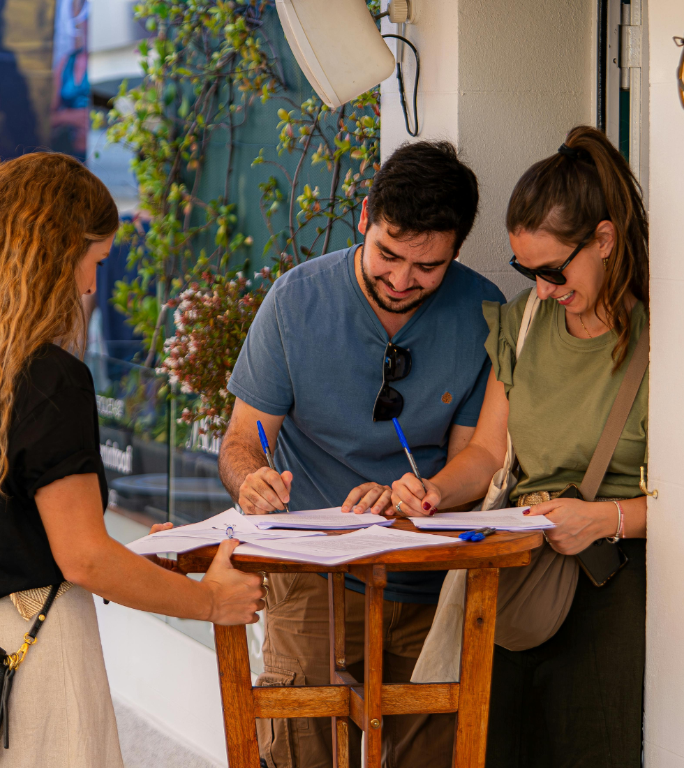 Two happy people signing papers at a table in an outdoor setting