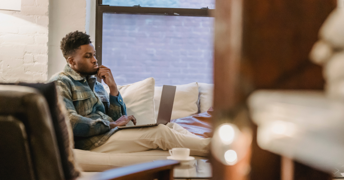 concentrated man using laptop while sitting on couch, reviewing website analytics to measure website ROI and business growth.